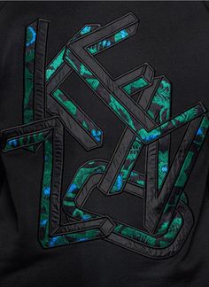 the back of a black jacket with green and blue designs on it, including letters