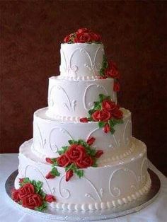 a three tiered white wedding cake with red roses