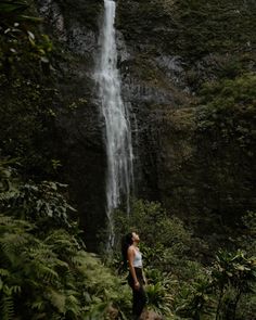 a woman standing in front of a waterfall