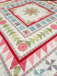 a quilted table topper with red and green trimmings on the edges