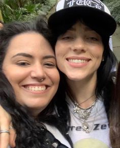 two women standing next to each other with their arms around one another and smiling at the camera