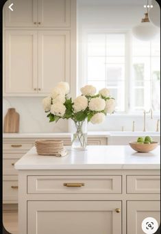 a vase filled with white flowers sitting on top of a kitchen counter