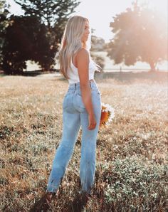 a woman standing in a field with her back to the camera