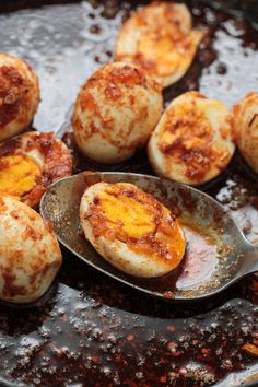 some food is being cooked in a skillet with spoons on the side,