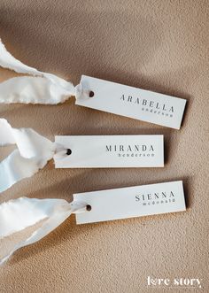 three white tags with the name miranda on them are tied to a tan carpet