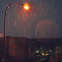 an image of a street light with rain coming down in the city at night time