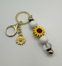 a keychain with a sunflower on it and two beads attached to it