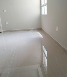 an empty room with white walls and tile flooring in the center is seen from across the room