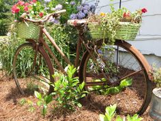 an old bicycle with baskets full of flowers in the front wheel is parked next to a house