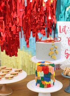 there is a cake and cookies on the table with red streamers in the background