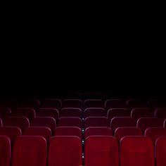 an empty theater with red seats and black walls