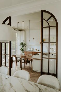 an open kitchen and dining room area with marble counter tops, white walls and wooden flooring