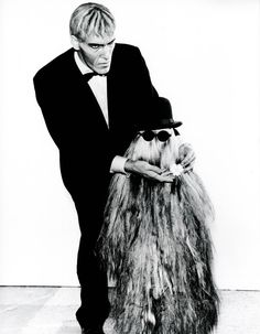 a man in a tuxedo is holding a large furry animal's tail