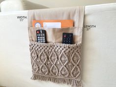 a couch with two remote controls in it and a pocket on the back that holds an envelope