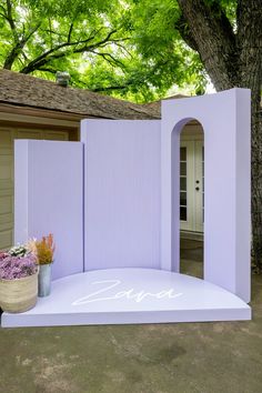 a large white arch with flowers in front of it