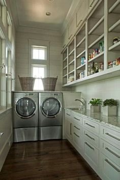 a washer and dryer in a small room with white cabinetry, wood flooring and open shelving