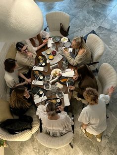 a group of people sitting around a table with food and drinks on it in a room