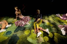 three women sitting on the ground with their legs spread out and one woman is laying down