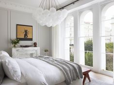 a bedroom with white walls and large windows