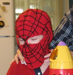 a young boy wearing a spiderman mask next to a toy rocket ship