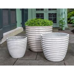 three large white planters sitting next to each other on a sidewalk in front of a building