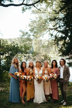 a group of people standing next to each other in front of trees and grass with flowers on their heads