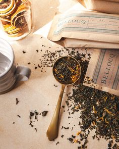 a spoon full of tea sitting on top of a table next to a bag of dried orange peels