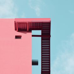 a pink building with red shutters on the side and a blue sky in the background