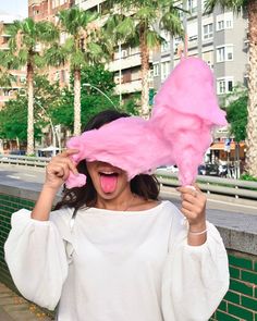 a woman holding up a pink object in front of her face