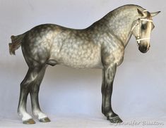 a statue of a grey horse standing on a white surface with its head turned to the side