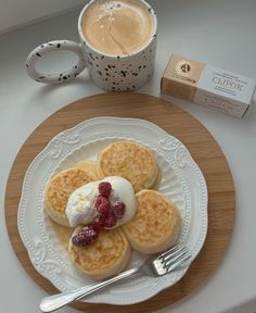 pancakes with whipped cream and raspberries on a plate next to a cup of coffee