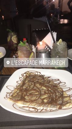 a white plate topped with chocolate sauce and waffles on top of a table