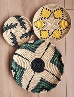 three woven baskets sitting on top of a wooden floor, each with different designs and colors