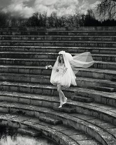 a woman in a wedding dress is walking down the stairs with her veil over her head