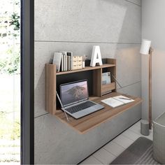 a laptop computer sitting on top of a wooden shelf next to a wall mounted lamp