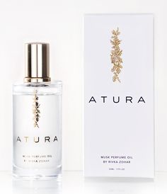 a bottle of perfume sitting next to a box on a white surface with the word atura written in gold