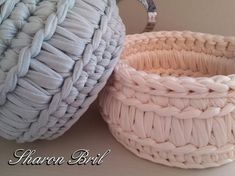 two baskets sitting next to each other on top of a white table with an iron hook