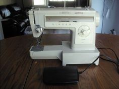 a white sewing machine sitting on top of a wooden table