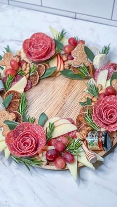 a wreath made out of apples, grapes and meats on a marble counter top