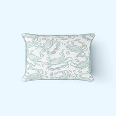 a white and green pillow on a light blue background with sea creatures in pastel colors