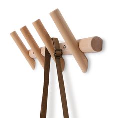 three wooden pegs hang on the wall with leather straps, and one is holding a pair of scissors