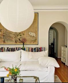 a living room filled with white furniture and bookshelves