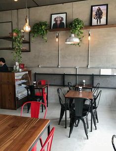 an empty restaurant with tables and chairs in front of the counter, hanging plants on the wall