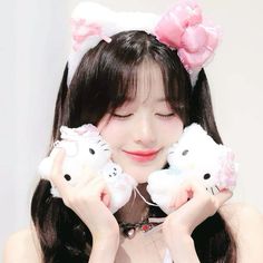 a girl holding two hello kitty stuffed animals in her hands and smiling at the camera