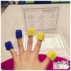 a person's hand with five fingers on top of it and four blue blocks in front of them