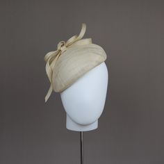 A flattering style hand blocked in ivory sinamay straw. Simply decorated with a knotted straw bow. An elegant headpiece perfect for any special occasion.  READY TO SHIP ONLY ONE AVAILABLE Secured to the head with an easy to hide millinery elastic that can be hidden under the hair. *One size fits all Construction: All of my hats have been constructed with the greatest care to detail. They are hand-blocked, stiffened and wired using traditional millinery techniques. I pride myself in using the fin Cream Fitted Hat For Ceremony, Fitted Cream Hat For Ceremony, Curved Brim Cream Straw Hat For Church, Elegant Hat With Structured Crown In Natural Color, Cream Straw Hat With Curved Brim For Church, Cream Curved Brim Straw Hat For Church, Adjustable Cream Straw Hat For Formal Occasions, Cream Adjustable Straw Hat For Formal Occasions, Cream Mini Hat For Summer Ceremony