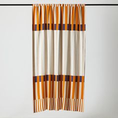 an orange and white striped curtain hanging from a metal rod with black pins on it