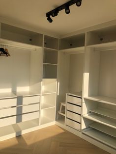 an empty closet with white shelves and drawers