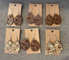 six pairs of wooden earrings with intricate designs on them sitting in front of a brown card