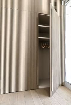 an open closet with shoes in it next to a sliding glass door that has vertical slats on the wall